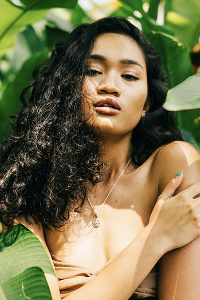 a brunette woman posing in the green leaves