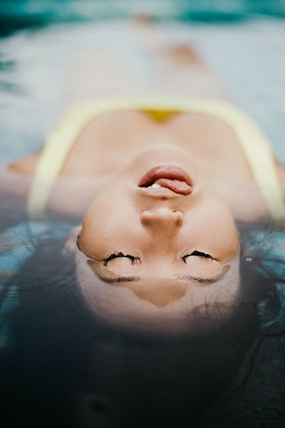 a woman lying with eyes closed and head above water adds a dramatic effect to the photo
