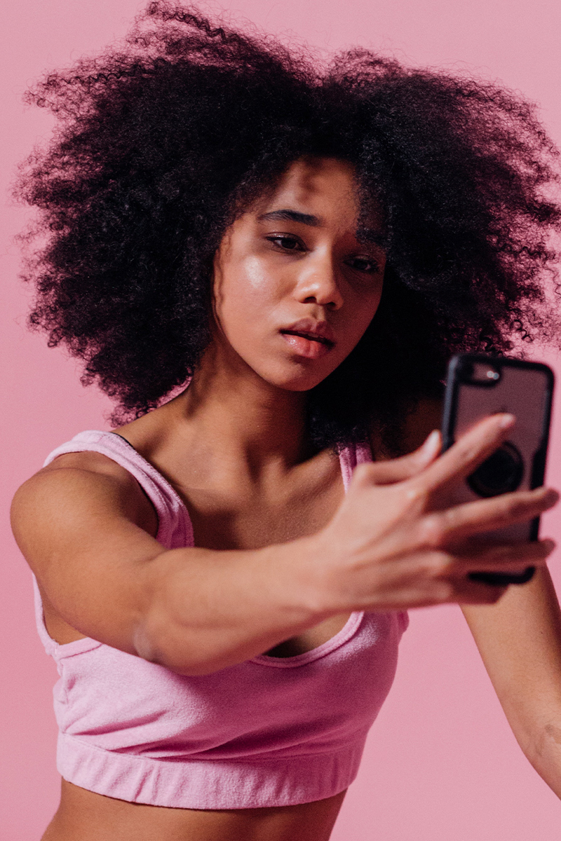 Woman on pink background taking a selfie