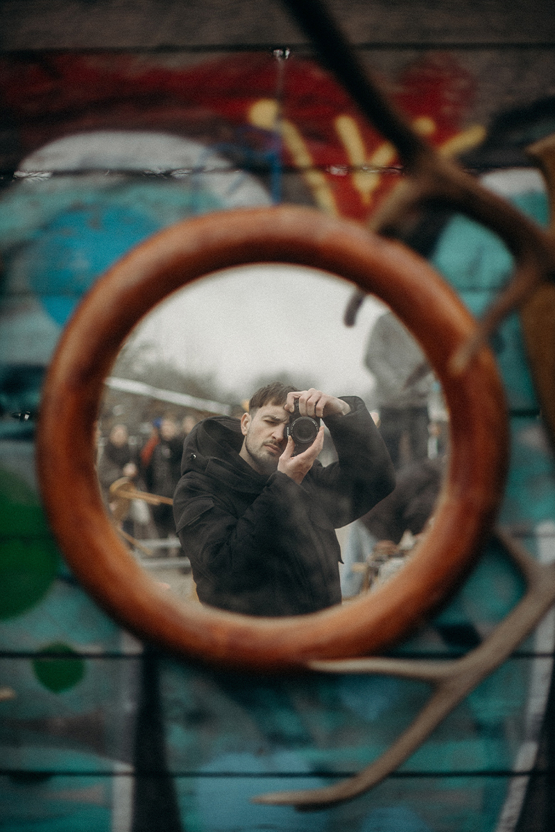 man with camera using outdoor mirror to take selfie