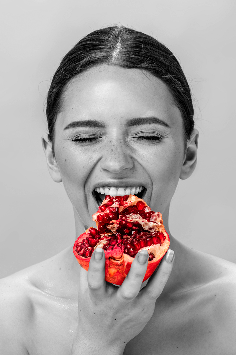A woman holding a colorized fruit on a black and white background