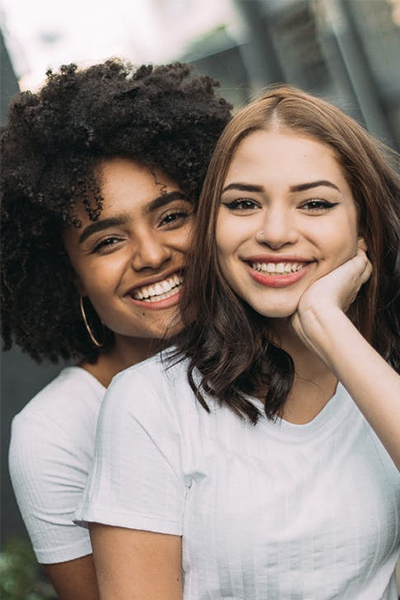 two girls in white t-shirts with wide smiles